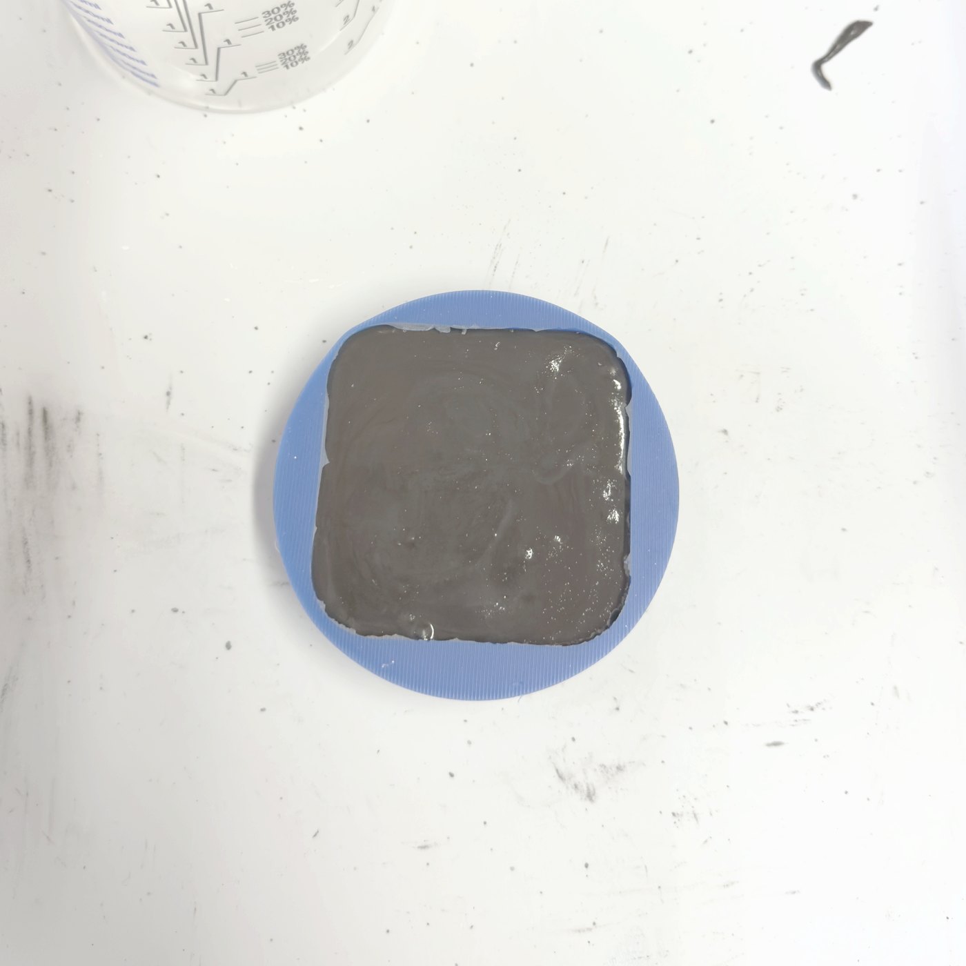 Wet grey concrete freshly poured into a blue silicone mold.